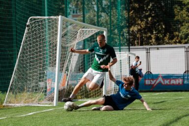 man in blue and white soccer jersey kicking ball on green grass field during daytime