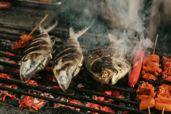 A bunch of fish are cooking on a grill